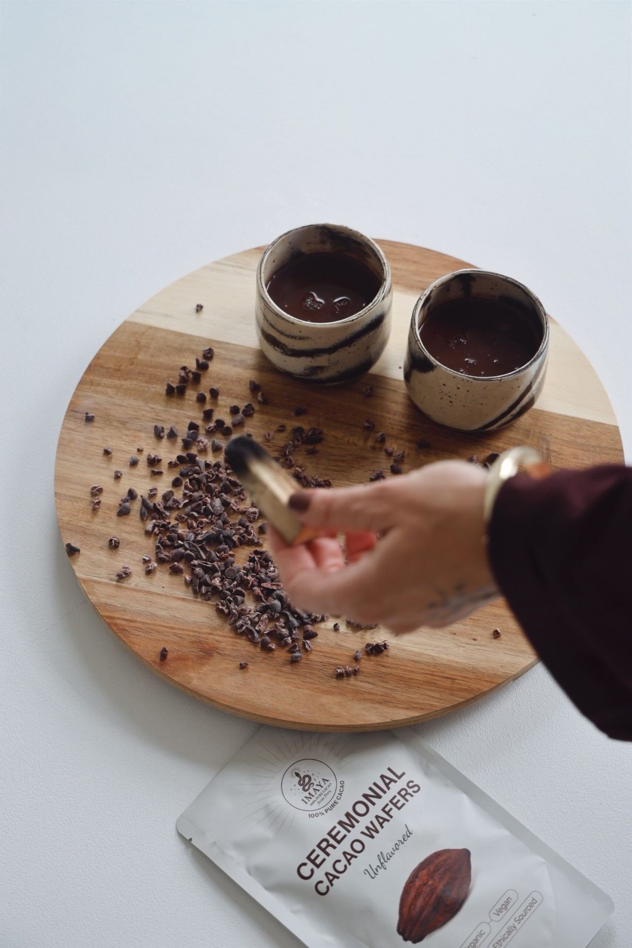 Vrouw schenkt cacao uit klei kannetje in beker